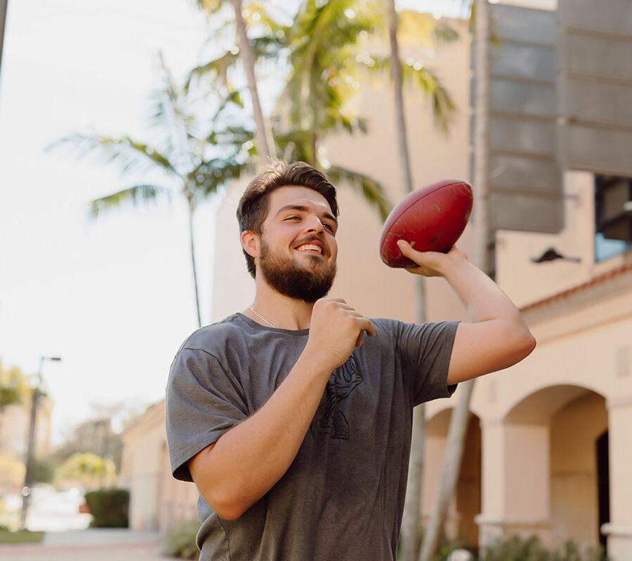 physical 教育 student throws a footb所有 on campus.